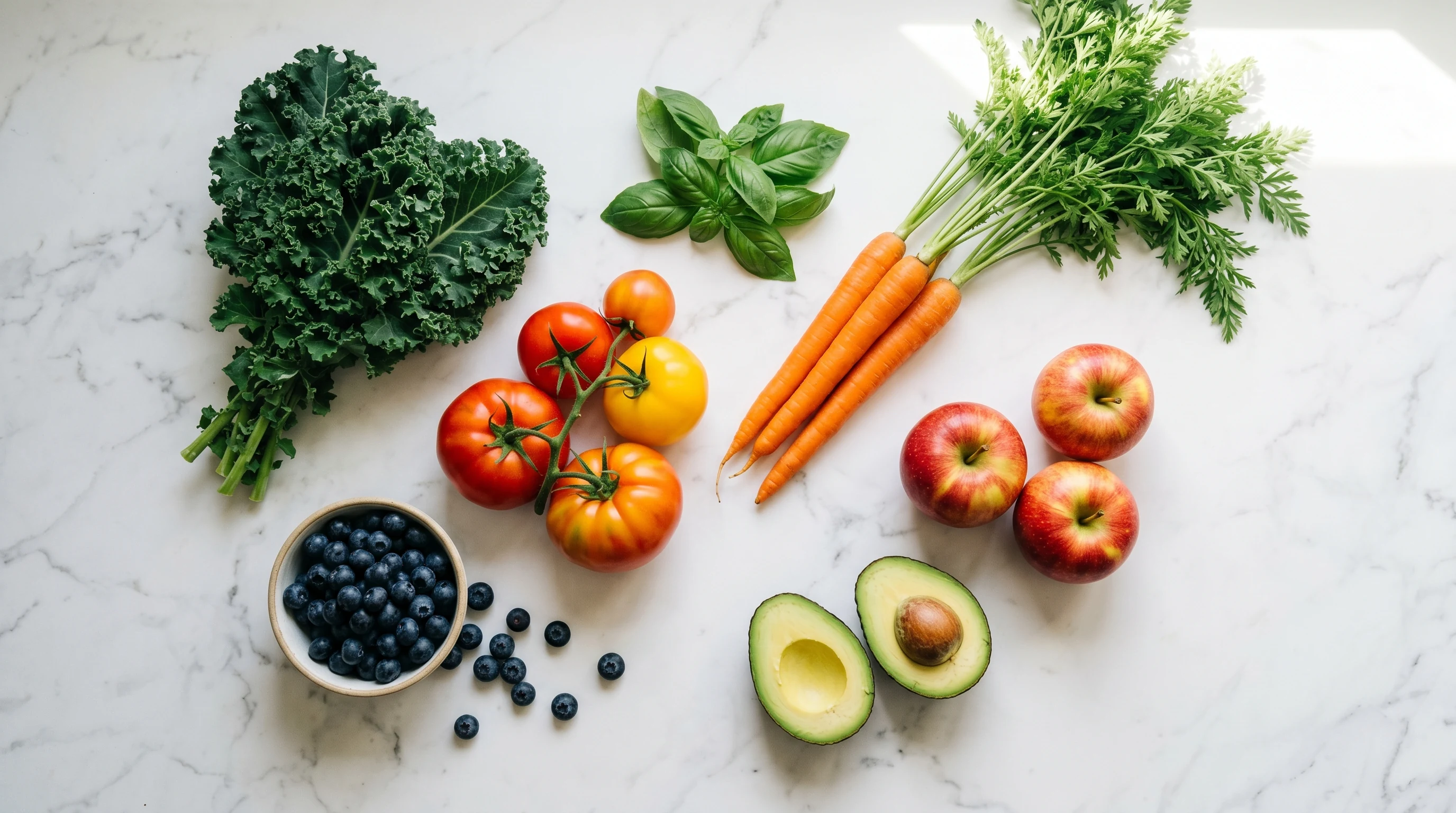 Fresh produce — kale, tomatoes, carrots, apples, blueberries, and avocado